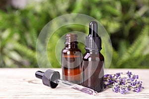 Bottles with natural lavender essential oil on white table against blurred background. Space for text
