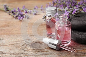 Bottles with natural lavender essential oil on wooden background