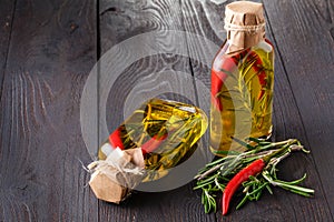Bottles with oil, herbs and spices at wooden table on black back