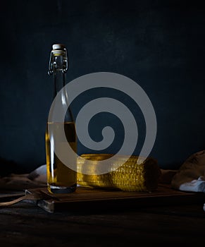 Bottles with oil, herbs and spices at wooden table on black background