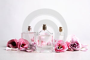 Bottles of perfume and beautiful flowers on light table