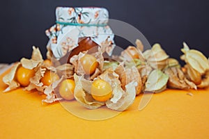 Bottles with physalis jam  and fresh  fruit  on orange