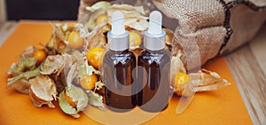 Bottles with physalis oil  and fresh  fruit  on orange