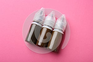 Bottles of pigments for permanent makeup on pink background, top view photo
