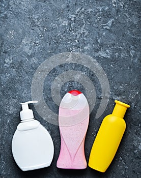 Bottles of products for showering on a black concrete surface. shampoo, soap, shower gel. Copy space. Top view. Flat lay