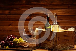 Bottles of red and white wine, glass and grape on a wooden inter