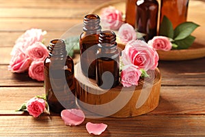 Bottles of rose essential oil and fresh flowers