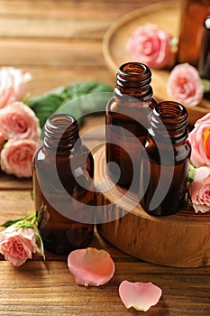Bottles of rose essential oil and fresh flowers
