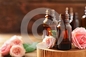 Bottles of rose essential oil and fresh flowers on table. Space for text