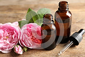 Bottles of rose essential oil, pipette and flowers