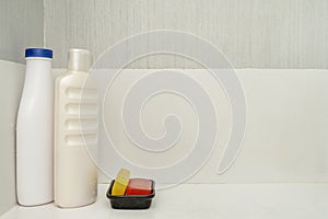 bottles of shampoo and brightly colored glycerin soap bars inside a shower room with a white dish