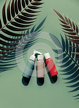 bottles with shampoo, lotion and cream green background with palm leaves
