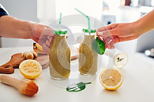 Bottles with spinach and banana smoothie with ingredients. People holding drinks. Healthy detox diet
