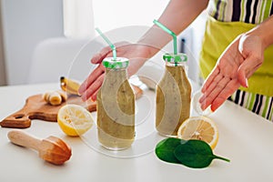 Bottles with spinach and banana smoothie with ingredients. Woman cooked drinks. Healthy detox diet