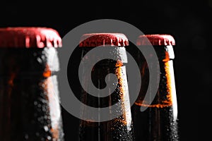 Bottles of tasty cold beer on black background, closeup