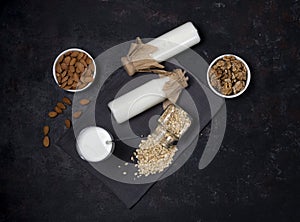 bottles of vegan plant-based milk made from seeds and nuts. flat lay on black background