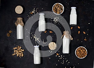 bottles of vegan plant-based milk made from seeds and nuts. flat lay on black background