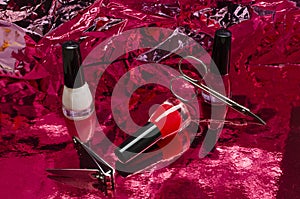 Bottles of white and red nail polishes, accessoris for nail care on th bright rd background
