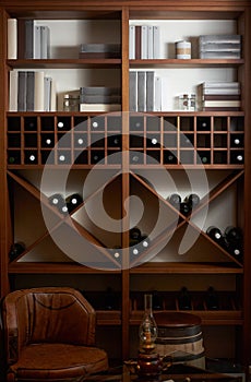 Bottles of white and red wine on a wooden shelf with books in pr