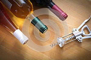 Bottles of wine with a corkscrew on wood table
