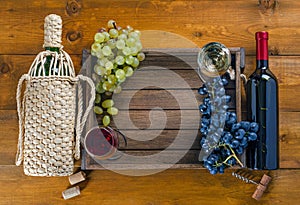 Bottles with wine and grapes in  box on  wooden background