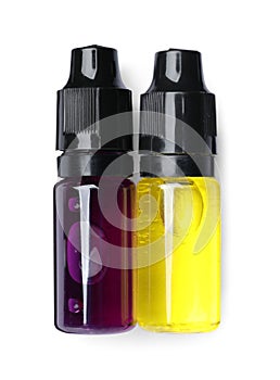 Bottles with yellow and purple food coloring on white background, top view