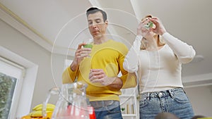 Bottom angle view of fit healthy young couple drinking healthful green smoothie at home in the morning. Healthy