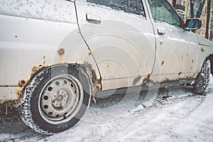 The bottom of the doors and the bottom of the white car in winter is covered with a caustic iron defect
