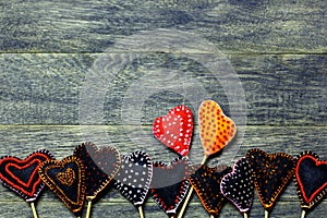 Bottom frame border of Handmade felt hearts on dark old wooden background.