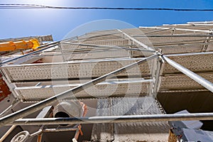 Bottom shot on scaffold placed against unfinished edifice, mixer and thermal insulation material are in the building