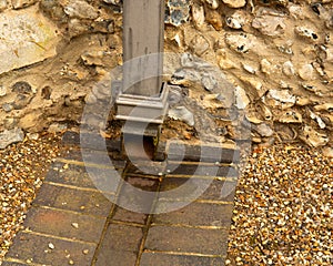 Bottom of sturdy square downspout where the rainwater is channeled off into drain