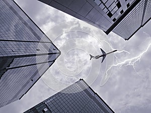 Bottom view of airplane flying above skyscraper
