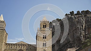 Bottom view of the ancient towers and a huge rock with growing trees on its top on blye sky background. Action. Concept