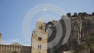 Bottom view of the ancient towers and a huge rock with growing trees on its top on blye sky background. Action. Concept