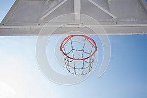 Bottom view of the background of a basketball hoop against the blue sky.