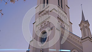 Bottom view of a beautiful facade of a historical building on a blue sky background. Action. Old church building with a