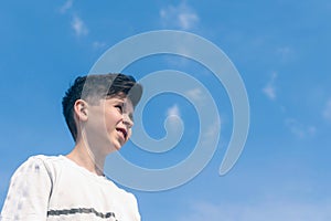 Bottom view a boy face on the blu sky background. Travel concept.