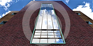 Bottom view of the catholic church huge window against the blue cloudy sky. Dark red brick facade finishing. 3d rendering