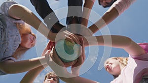Bottom view of children holding the earth: the future is in their hands