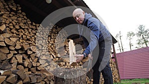 Bottom view of confused man with a log and a sharp vintage axe chop wood for fire heat. Chopping wood for the first time