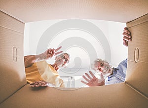 Bottom view of a couple of smiling elderly people moving house and opening packing boxes