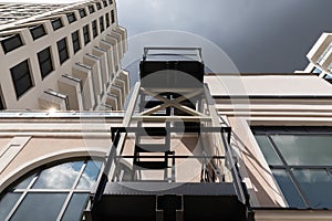 Bottom view of dark metal pompier ladder of luxury apartment building with many floors. Dark sky background, bad weather photo