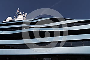 Bottom view of decks of huge yacht of blue color at sunny day, glossy board of the motor boat, sun reflection on glossy