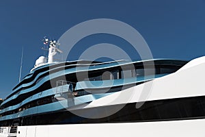 Bottom view of decks of huge yacht of blue color at sunny day, glossy board of the motor boat, sun reflection on glossy