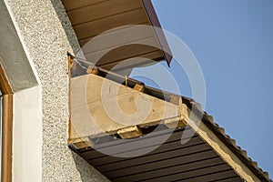 Bottom view detail of new modern house cottage corner with stucco walls, brown shingled roof and unfinished siding installation o