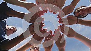 Bottom view of diverse teenagers making circle of hands with palms down