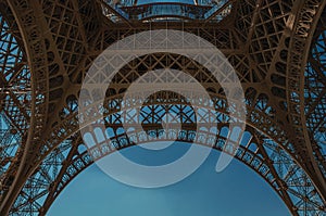 Bottom view of Eiffel Tower made in iron and Art Nouveau style, with sunny blue sky in Paris.