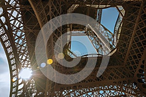 Bottom view of Eiffel Tower made in iron and Art Nouveau style, with sunny blue sky in Paris.