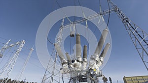 Bottom view of electricity grid and transformer on blue cloudy sky background. Action. Power line at the electricity