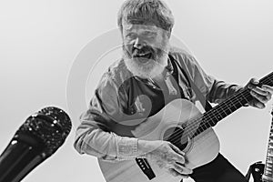 Bottom view of emotional senior bearded man, musician playing guitar isolated on white background. Rehearsal base